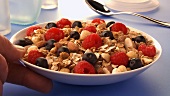 Putting a dish of muesli with berries on a table