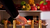 Hand taking bottle of champagne out of refrigerator