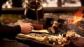 Man drinking coffee by campfire