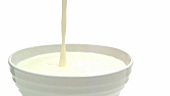Pouring milk into a bowl (close-up)