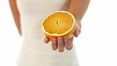 Junge Frau hält eine halbe Orange
