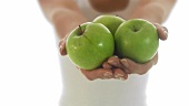 Junge Frau hält drei grüne Äpfel