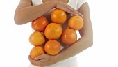 Junge Frau hält mehrere Orangen