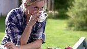 Frau macht Kaffeepause beim Heimwerken im Garten