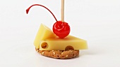 Emmental cheese & cocktail cherry on cocktail stick on cracker