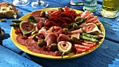 Plate of antipasti: salami, ham, figs, olives, asparagus