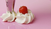 Cream rosettes with one strawberry on pink plate