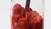 Pureeing strawberries with a hand blender