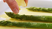 Sprinkling green asparagus with lemon juice