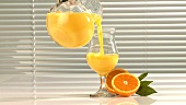 Ein Glas Orangensaft einschenken
