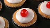 Cupcakes with cocktail cherries in muffin tin