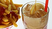 Chips with ketchup and a glass of cola with ice cubes