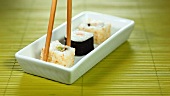 Taking California maki out of a dish with chopsticks
