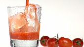 Tomatensaft in ein mit Eiswürfeln gefülltes Glas gießen