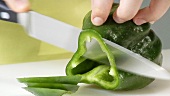 Eine grüne Paprika in Ringe schneiden