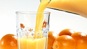 Orangensaft aus der Kanne in ein Glas gießen