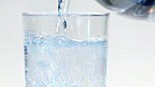 Pouring mineral water into a glass (close-up)