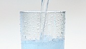 Wasser in ein Glas mit Crushed Ice gießen (Close Up)