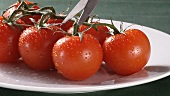 Eine Tomate von der Rispe schneiden