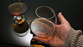 Cognac in zwei Gläsern, Hand nimmt ein Glas weg