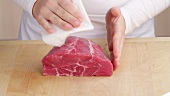 Patting a shoulder of beef dry