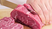 Cutting a shoulder of beef into thick slices