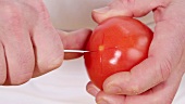 Scoring a cross into the bottom of a tomato