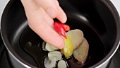 Placing lemon zest and chilli rings in a saucepan