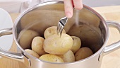 Taking potatoes boiled in their skins out of a pan