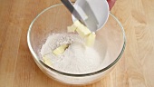 Pieces of butter being added to sieved flour