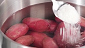 Salt being added to a pot of potatoes
