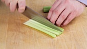 A peeled celery stick being diced