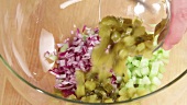 Gherkins being added to chopped vegetables