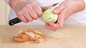 An onion being peeled and finely chopped