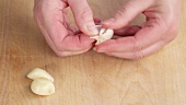 Garlic being crushed with a knife with a knife and peeled