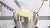 Butter being added to a saucepan and melted