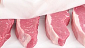 New York strip steaks being patted dry