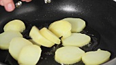Kartoffelscheiben in eine Pfanne geben