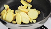 Potato slices being fried in a pan