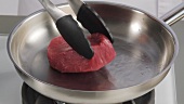 A fillet steak being fried in a pan