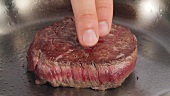 Testing the doneness of a fillet steak by gently pressing the middle