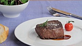 A beef fillet steak with herbs and a tomato