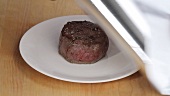 A fried fillet steak being covered with tin foil