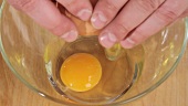 Ein Ei in eine Schüssel aufschlagen