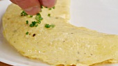An omelette being sprinkled with chives