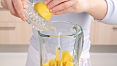 Lemon juice being added to mango pieces in a blender