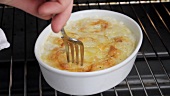 Doneness of potato gratin being tested