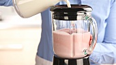 Milk being added to a strawberry and vanilla ice cream mixture