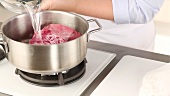 Cold water being added to beef in a pot