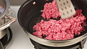 Minced meat being fried in oil in a pan